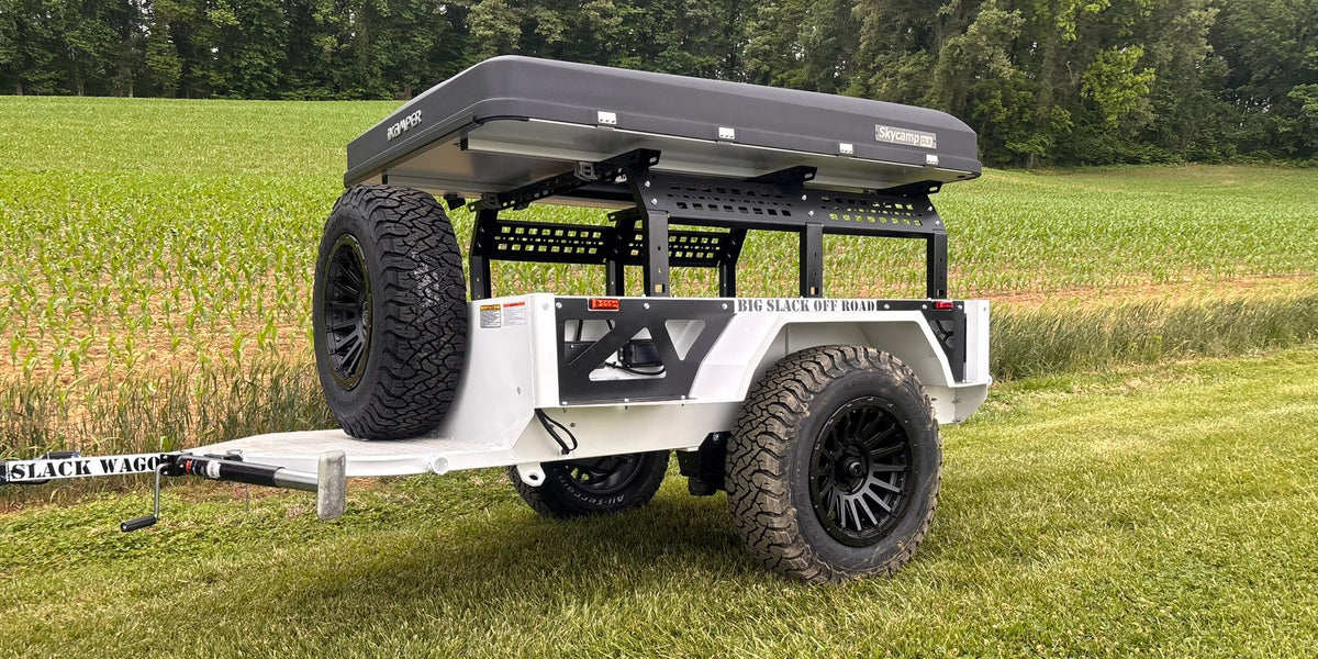 White Big Slack Off Road Slack Wagon trailer with rooftop tent and spare tire, front three-quarter view