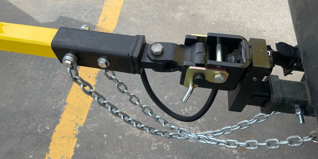 Articulating hitch and safety chains on a yellow Slack Wagon tongue